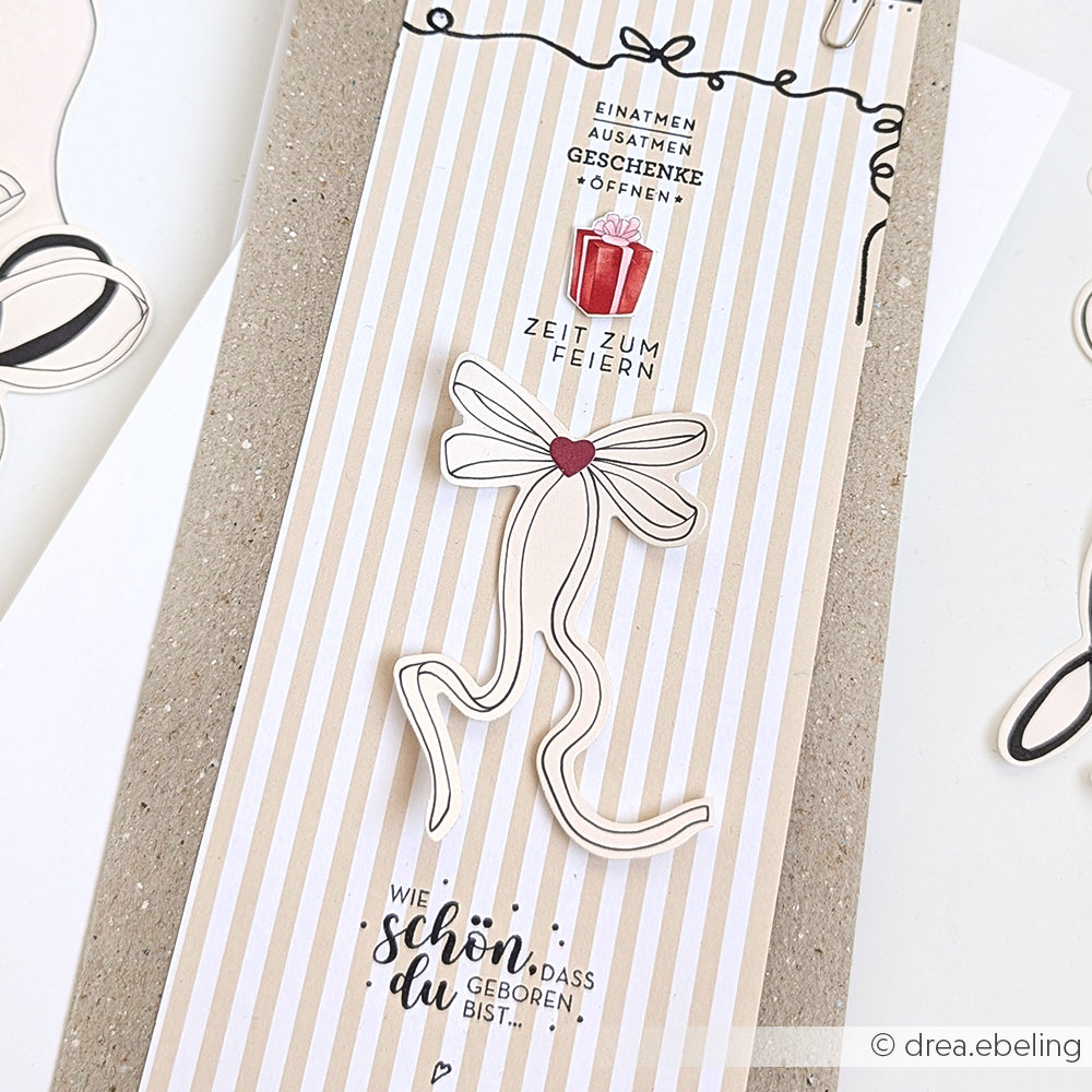 Eine gestreifte Karte von Alexandra Renke mit einem roten Geschenk, weißem Band und deutschen Geburtstagswünschen - ideal für Papierprojekte oder in Kombination mit Ihrem Lieblingsholzstempel.