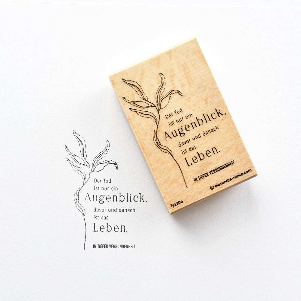 Ein Holzstempel von Alexandra Renke mit deutschem Text und einem Pflanzenmotiv, abgebildet neben dem gestochen scharfen Tintenabdruck auf weißem Papier - ideal für kreative Papierprojekte.