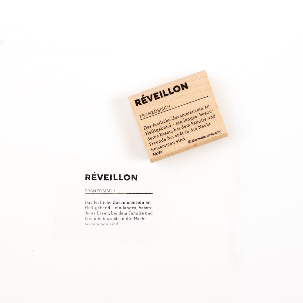 Ein Holzstempel und eine bedruckte Karte mit dem Wort „Réveillon“ und dessen Definition – perfekt für Papierprojekte.