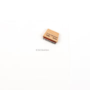 Ein Mini-Typo-Stempel aus Holz mit der Aufschrift „FI FA FIRLEFANZ“ und dessen Abdruck auf weißem Hintergrund.