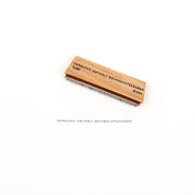 Ein Stempel aus Holz mit der Aufschrift „VORSICHT! ENTHÄLT WEIHNACHTSZAUBER“, der neben dem Stempel selbst ausgestellt ist.
