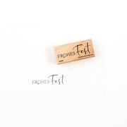 Ein Holzstempel mit der Aufschrift „Frohes Fest“ und dem dazugehörigen Stempelabdruck darunter.