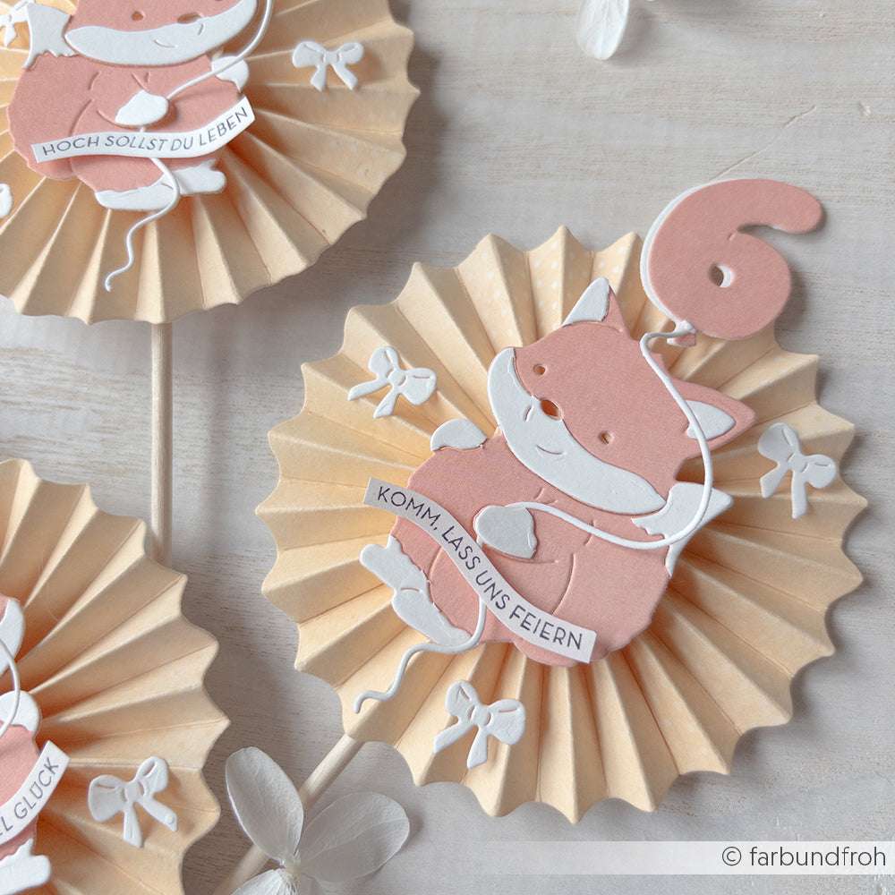 Papierrosette von Alexandra Renke aus hochwertigen Materialien mit einer rosa Katze mit Luftballon und "Komm, lass uns feiern"-Banner - perfekt für Papierprojekte und kreative Dekorationen.