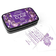 Tsukineko VersaFine Clair Purple Stempelkissen mit floralem Muster, daneben zwei weiße, mit Pigment-Tinten gestempelte Anhänger.