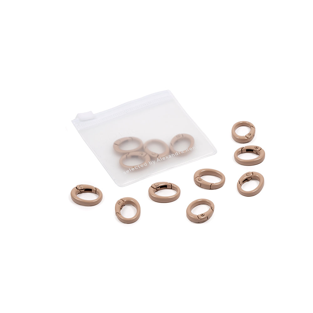 Neun kleine goldene ovale Karabiner und ein durchscheinendes Säckchen auf weißem Hintergrund – ideal für DIY-Projekte oder zum Gestalten individueller Handyketten.