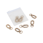 Sechs beigefarbene Schlüsselanhänger mit Ringen und einem mattierten Beutel auf weißem Hintergrund – ideal für DIY-Projekte oder als stilvolle Handyketten mit ovalen Karabinern.