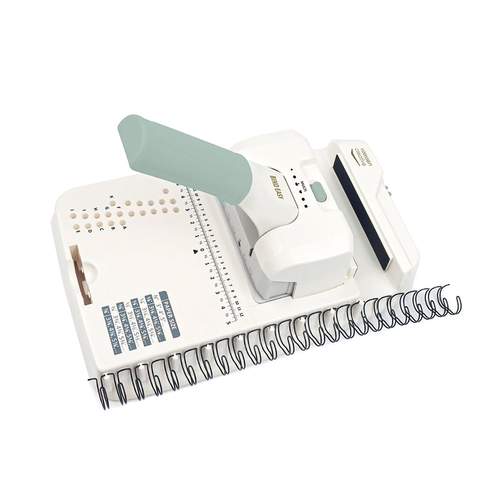 Die Vaessen Bindemaschine verfügt über einen Griff, ein Lineal und Metallspulen am Rand für die Drahtkammbindung (von oben).