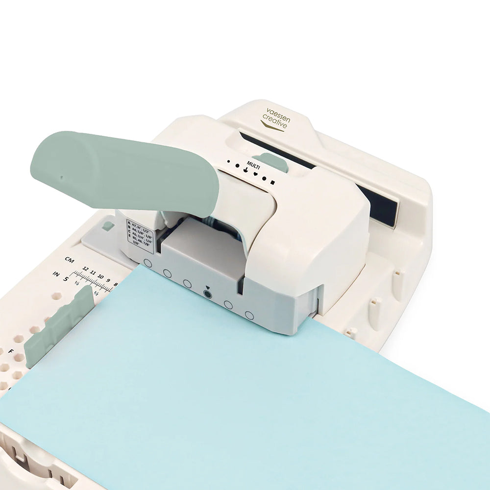 Eine Nahaufnahme einer weißen Vaessen Bindemaschine mit tealfarbenem Griff und blauem Papiereinsatz, ideal für präzises Stanzen bei Disc-Bindung Projekten.