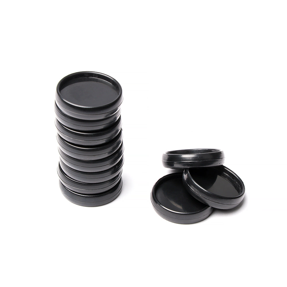 Ein Stapel schwarzer Vaessen-Kunststoffdeckel, perfekt als Bindescheiben für flexible Bindung, steht neben drei losen Deckeln auf weißem Hintergrund.