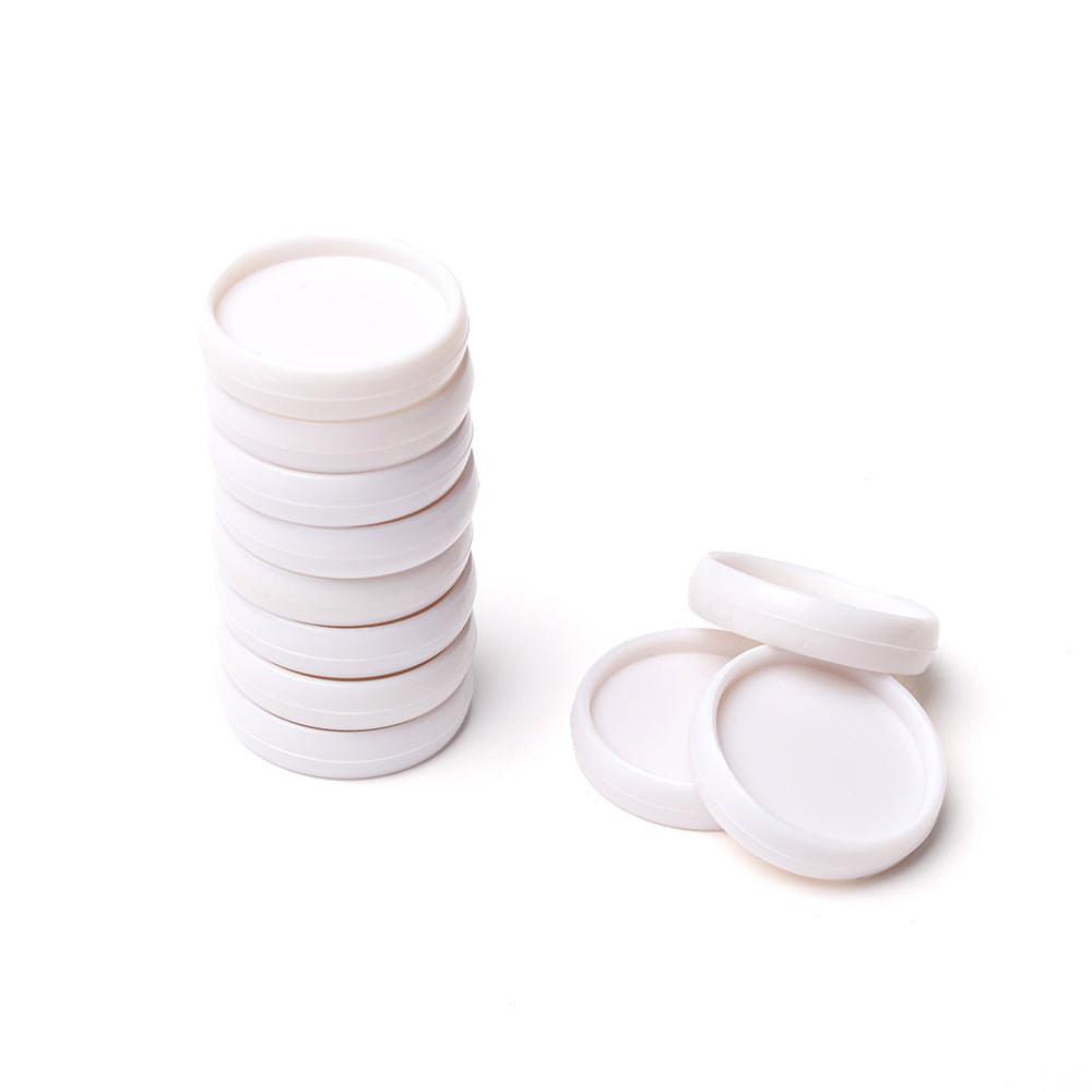 Ein Stapel weißer Vaessen-Plastik-Bindescheiben liegt neben ein paar losen Deckeln auf weißem Hintergrund.
