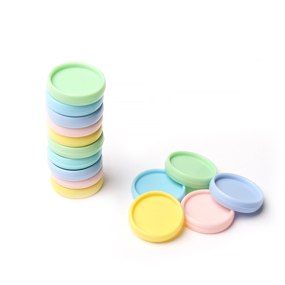 Auf der linken Seite befindet sich ein Stapel pastellfarbener runder Vaessen Bindescheiben-Deckel, auf der rechten Seite sind weitere verstreut - perfekt für die individuelle Gestaltung von Notizbüchern und Planern -, die vor einem weißen Hintergrund präsentiert werden.