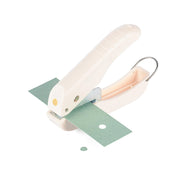 Eine weiße Stanzzange in Handgröße stanzt ein perfektes Kreismotiv aus einem grünen Stück Papier – ideal für Papierprojekte.