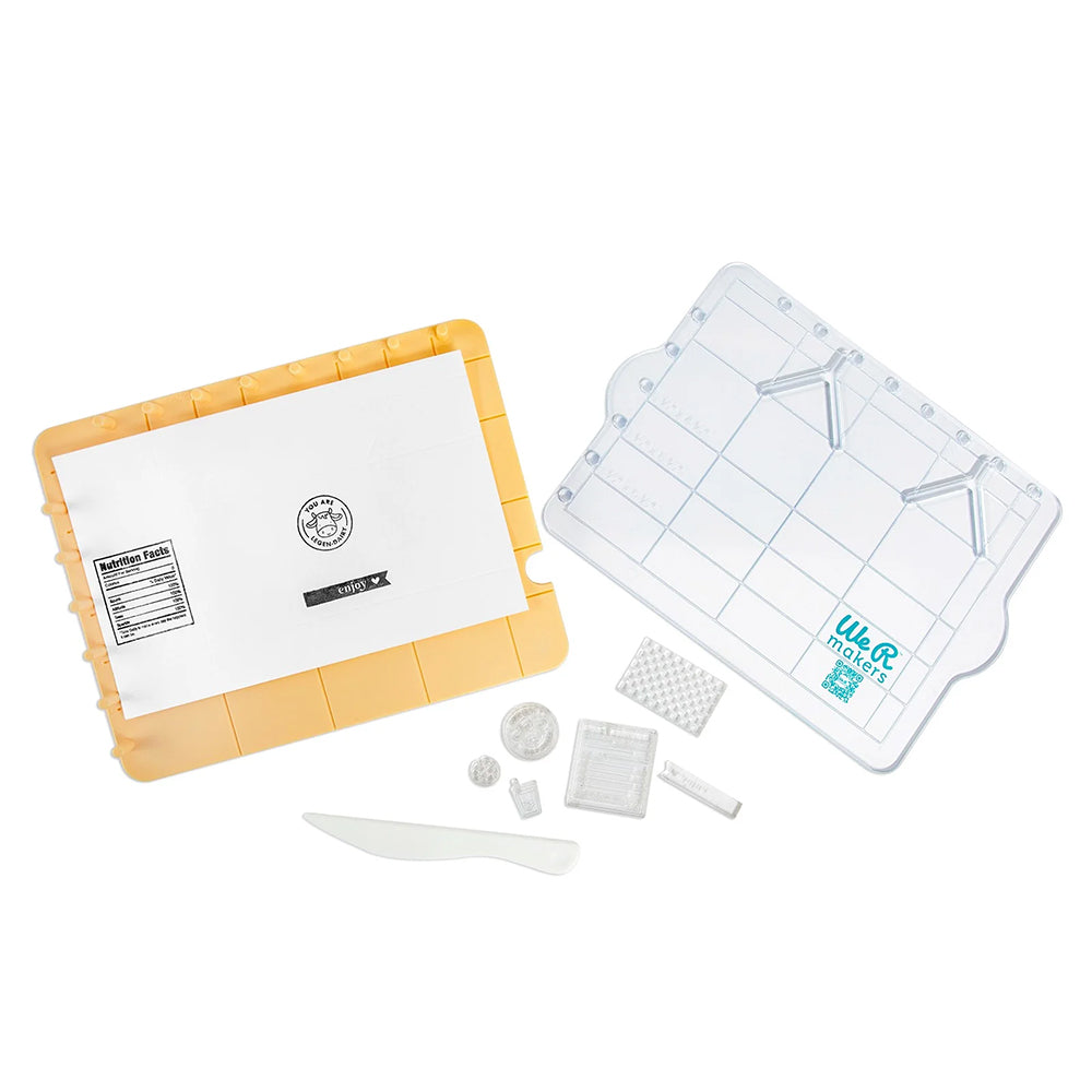 Eine gelbe Formenschachtel, eine durchsichtige Schale, ein weißes Messer und verschiedene kleine weiße Formen, angeordnet auf weißem Hintergrund – perfekt, um Inspiration für Ihre nächsten Papierbastelprojekte zu finden oder 3D-Papierdekorationen mit Details zu verfeinern.