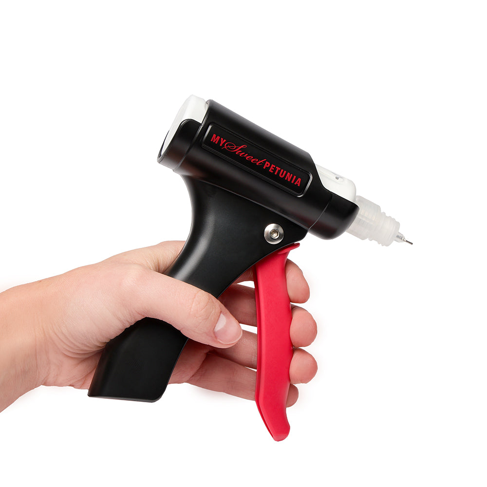 Eine Hand hält eine schwarz-rote Vaessen Präzisions-Klebepresse mit einer kleinen Nadelspitze, die sich perfekt zum Auftragen von Klebstoff beim Papierbasteln eignet.