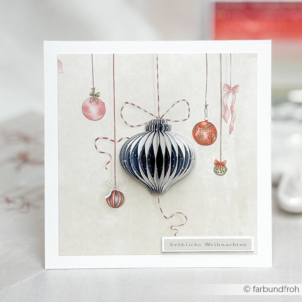 Handgemachte Weihnachtskarte von Alexandra Renke mit einer 3D PAPPcut Ornamentkugel und hängenden Kugeln mit "Fröhliche Weihnachten" Text. Ideal für Fans von Buchbinden und kreativen Stahlbandstanzen.
