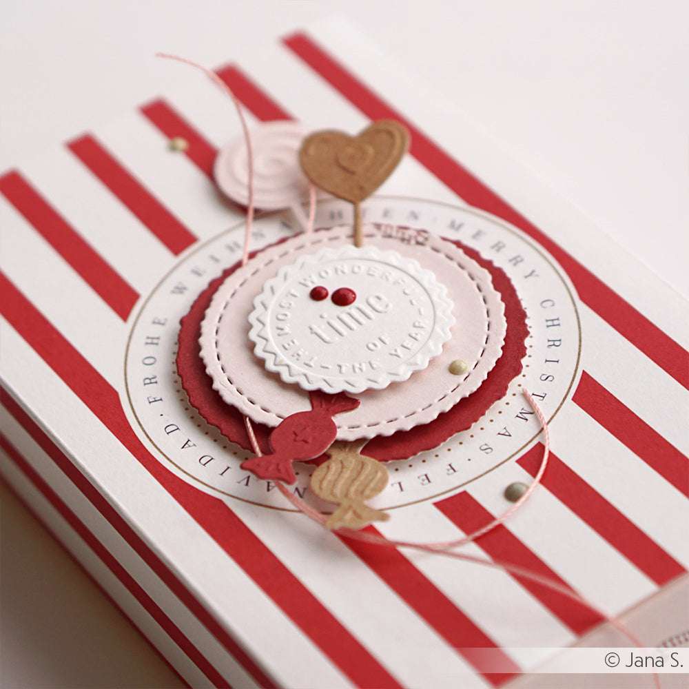 Die rot-weiß gestreifte Geschenkbox von Alexandra Renke mit geschichteten Papierkreisen, Herzen und festlichen Akzenten wurde mit Stanzsystemen und einem Cut & Emboss Folder hergestellt - ideal, um Ihren Weihnachtsgeschenken einen Ho Ho Ho Touch zu verleihen.