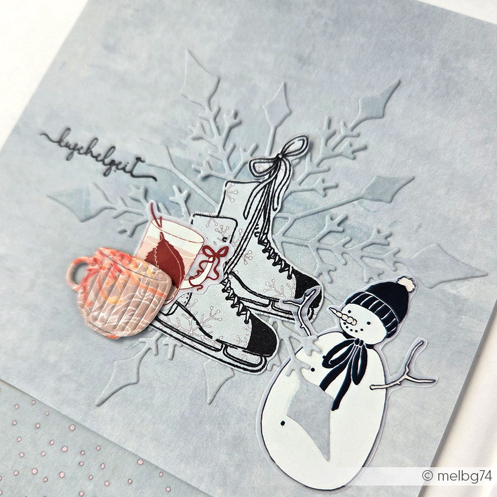 Handgefertigte Alexandra Renke Winterkarte mit Schlittschuhen, einem Becher und einem Schneemann auf hellblau mit Schneeflocken - perfekt für Transferfolien Basteln oder zum Hinzufügen von charmanten Winterwald Motiven.