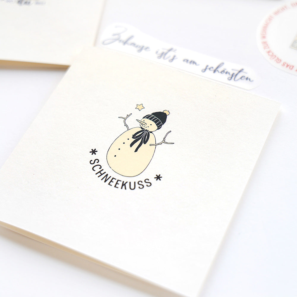 Illustration eines lächelnden Schneemanns mit Mütze und Schal und "Schneekuss" darunter - perfekt für Alexandra Renke Bastelprojekte Winterwald oder bezaubernde Alexandra Renke Transferfolien Basteln Kreationen.