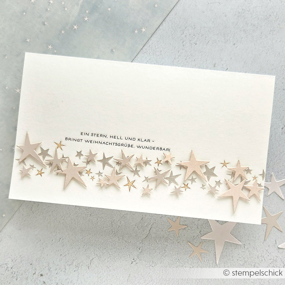 Eine weiße Alexandra Renke Karte mit geschichteten Sternausschnitten und deutschem Text, umgeben von Sternformen - ideal für Bastelprojekte Motive oder das Erstellen von Spezialeffekten mit Transferfolien Basteln.