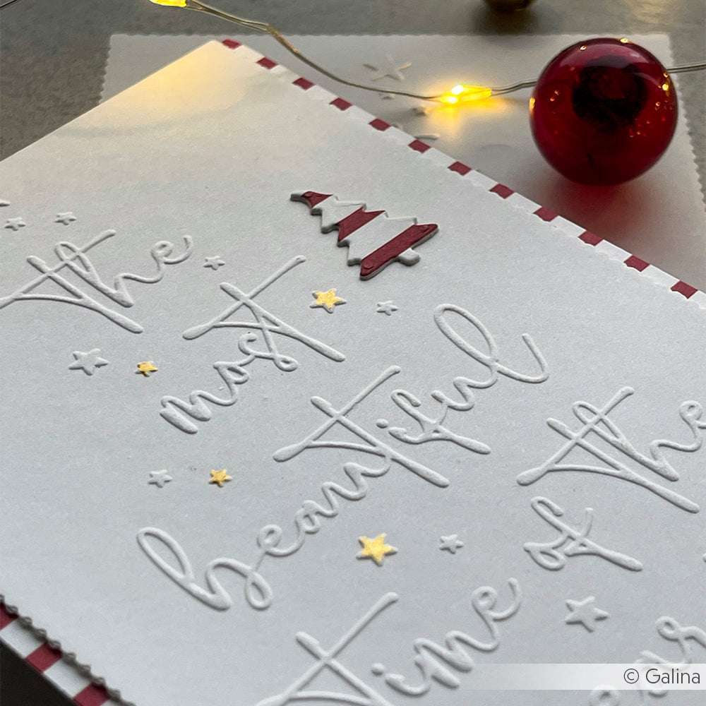 Eine festliche Karte mit dem Alexandra Renke Prägefolder, goldenen Sternen und einem roten Weihnachtsbaum, der von Lichtern und einem roten Ornament umgeben ist - perfekt für die Weihnachtszeit.