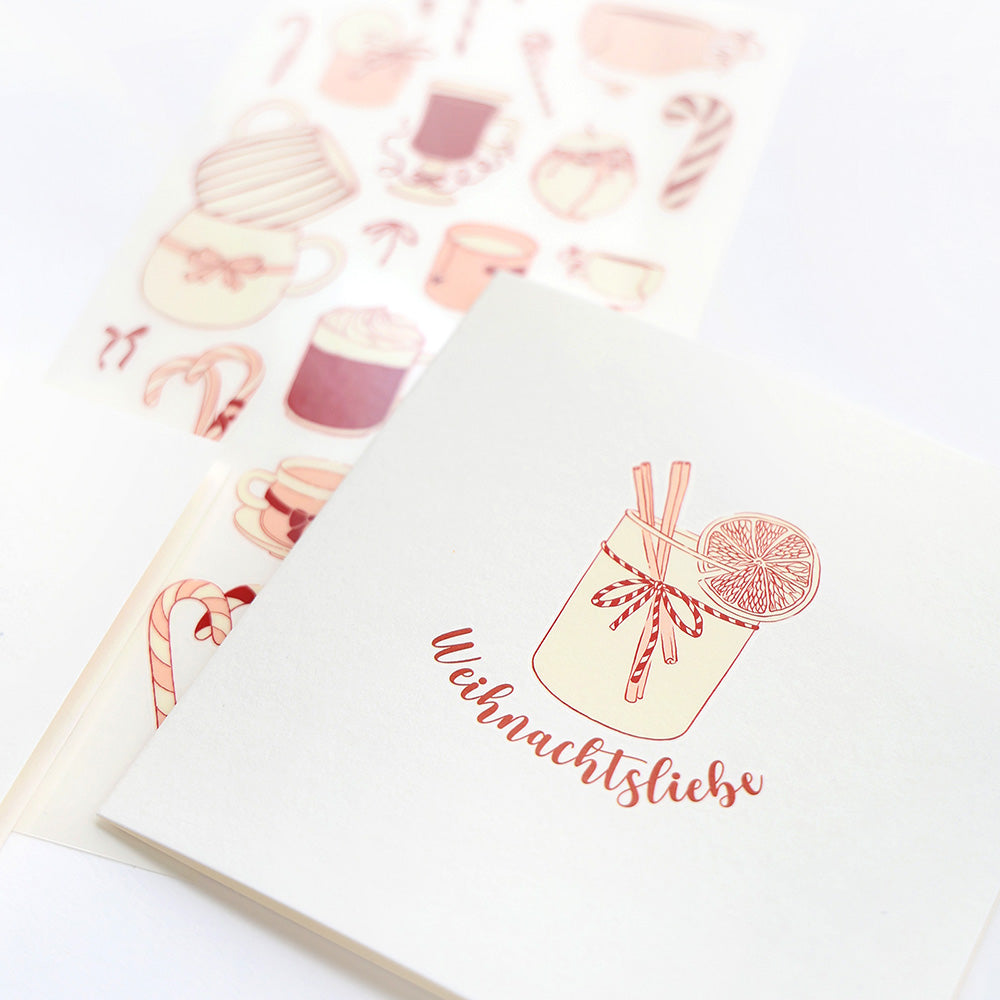 Eine festliche Alexandra Renke-Grußkarte mit Weihnachtsliebe und einem Festtagsgetränk ist gepaart mit Festtagsaufklebern mit Rub-On Festlichkeiten und gemütlichen Winterwärme Motiven Schriften Muster.