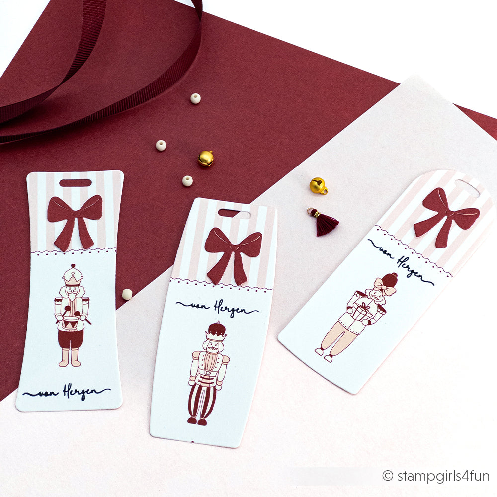 Drei Nussknacker-Lesezeichen mit roten Schleifen, auf kastanienbraunem und weißem Papier mit kleinen Perlen - perfekt für einen weihnachtlichen Touch mit den Rub-On Festlichkeiten Winterwärme Designs von Alexandra Renke.