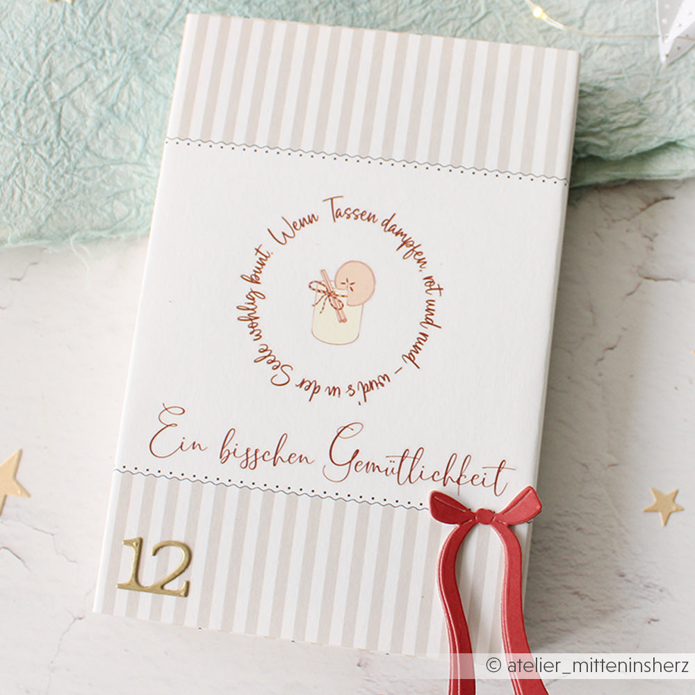 Eine gestreifte Karte von Alexandra Renke mit einer Baby-Illustration, deutschem Text, rotem Band, goldenem 12-Dekor und Transferfolien-Akzenten - ideal für einzigartige Bastelprojekte.