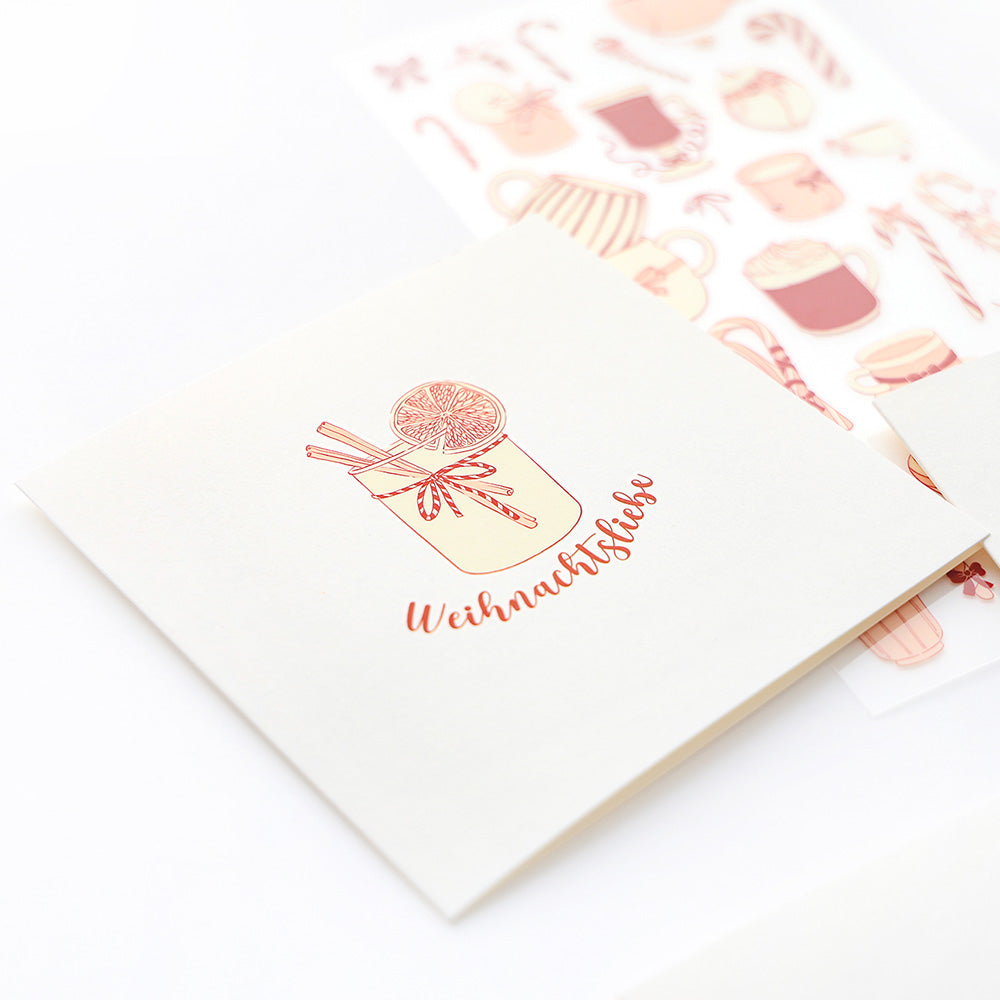 Die quadratische Karte von Alexandra Renke zeigt eine festliche Tasse und "Weihnachtsliebe", gepaart mit weihnachtlichen Winterwärme-Motiven - ideal, um Ihren Transferfolien-Bastelkreationen saisonalen Charme zu verleihen.