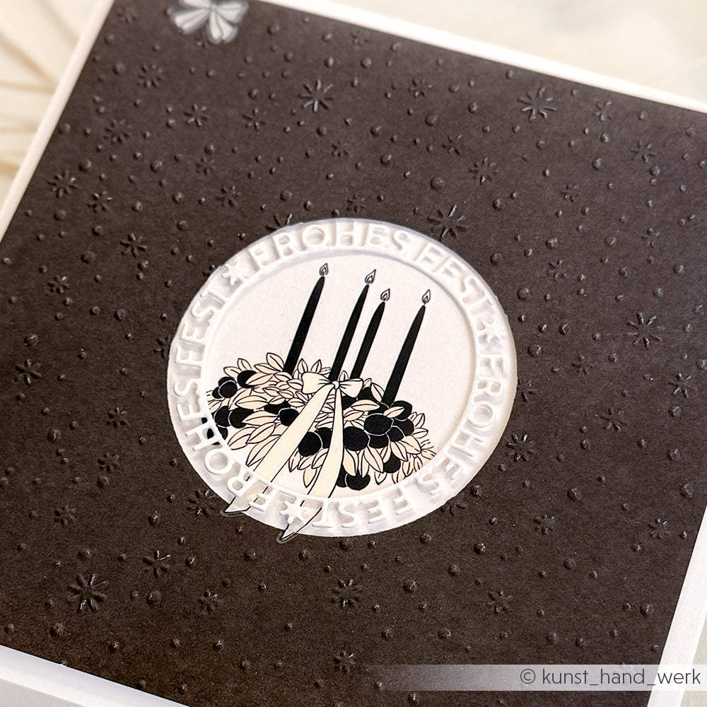 Schwarze Karte von Alexandra Renke mit geprägten Sternen und einem kreisförmigen Kerzenblumenmotiv mit "FROHES FEST" - perfekt für Bastelprojekte oder zur Verwendung mit Transferfolien.