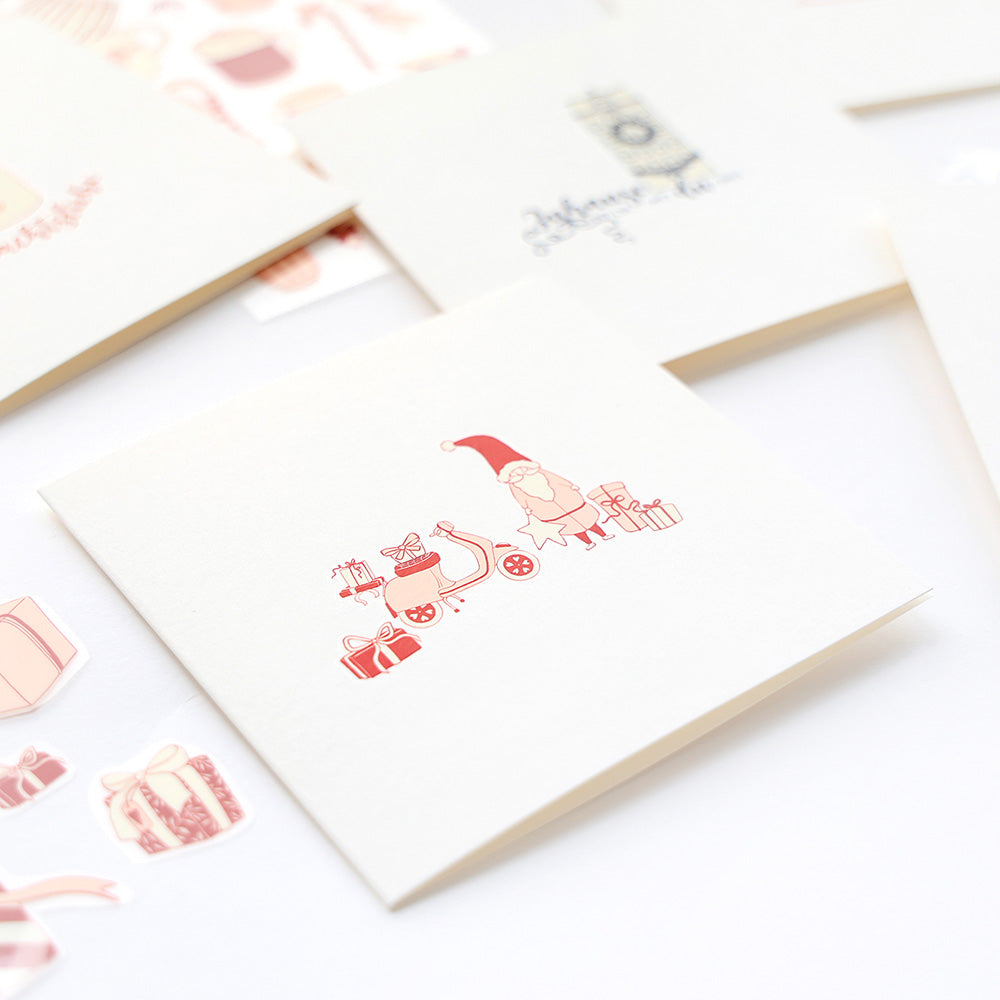 Eine Weihnachtskarte von Alexandra Renke mit dem Weihnachtsmann, Geschenken und einem Motorroller auf weißem Grund - ideal, um mit Weihnachtsdeko-Motiven oder Transferfolien-Basteln einzigartige Festtagsgrüße zu gestalten.