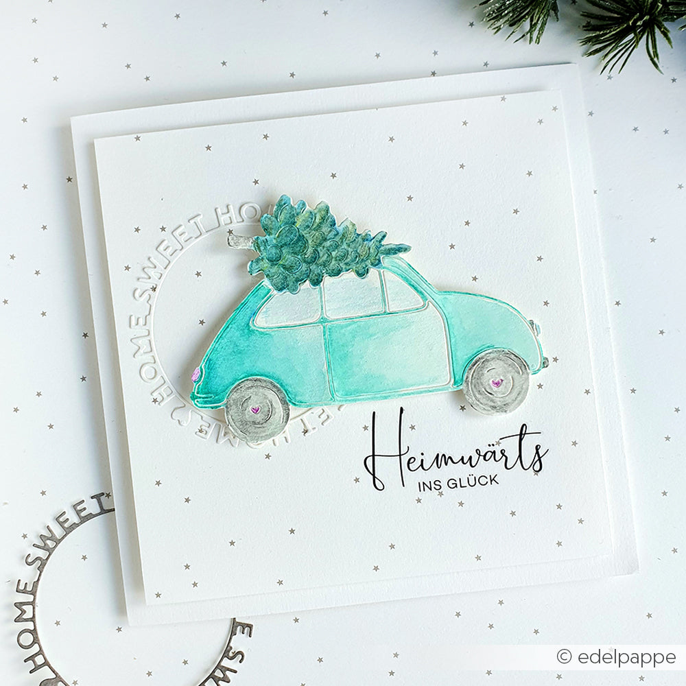 Ein aquarelliertes Auto mit einem Weihnachtsbaum auf dem Dach und "Heimwärts ins Glück" darunter - ideal für Bastelprojekte mit Alexandra Renke Weihnachtsglück Transferfolie.