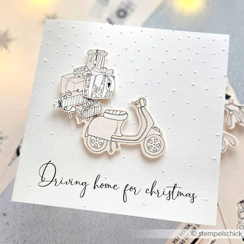 Handgefertigte Karte von Alexandra Renke mit einem Roller mit Weihnachtsgeschenken und dem Text "Driving home for Christmas", akzentuiert mit einer festlichen Textur aus einem Embossing Folder für einen leichten Schneefall-Effekt.