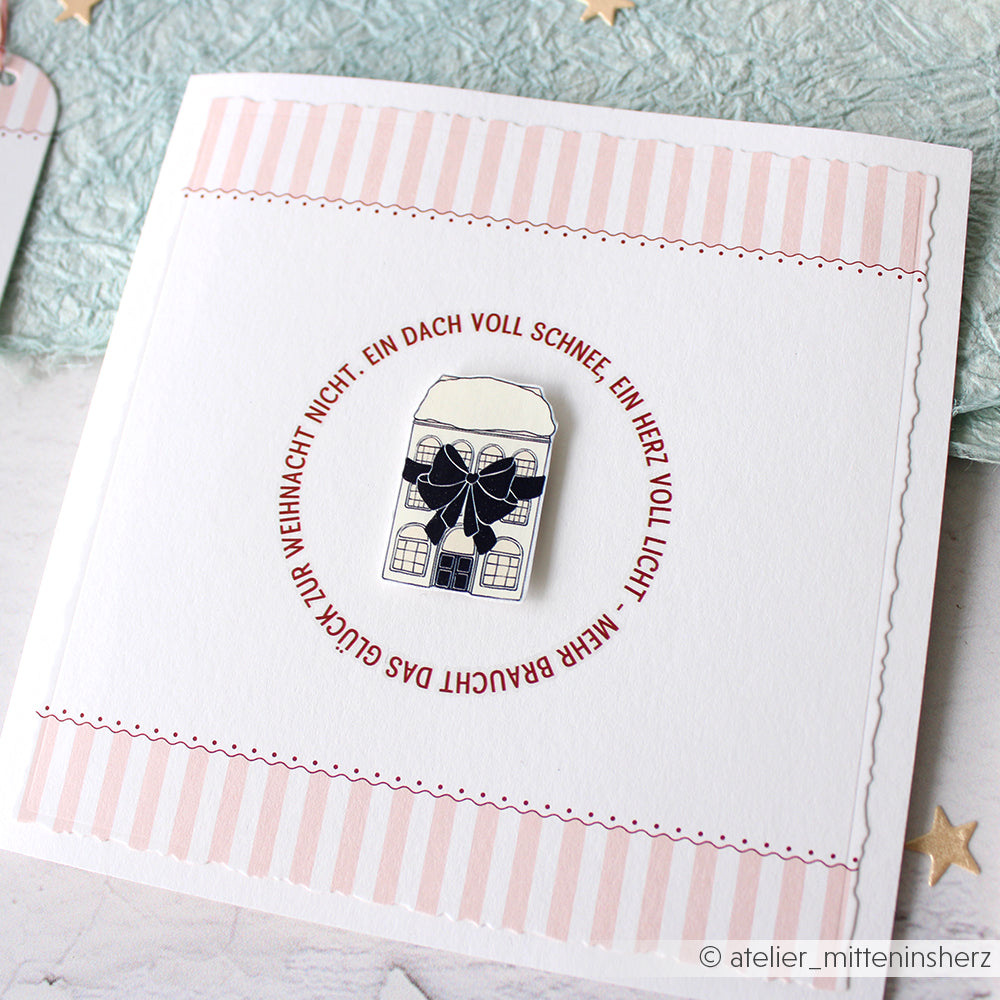 Quadratische Karte von Alexandra Renke mit einem Haus, einer Schleife und einem deutschen Feiertagstext, umrandet von rosa und weißen Streifen - ideal für Rub-On Festlichkeiten Winterheim oder Transferfolien Basteln Motive Schriften Muster Projekte.