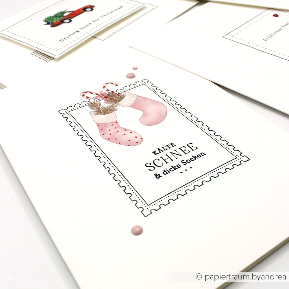 Weiße Karte von Alexandra Renke mit rosa gepunkteten Socken und dem Text "KALTER SCHNEE & dicke Socken" - ideal für Bastelprojekte zu Weihnachten oder als Rub-On Weihnachtszauber.