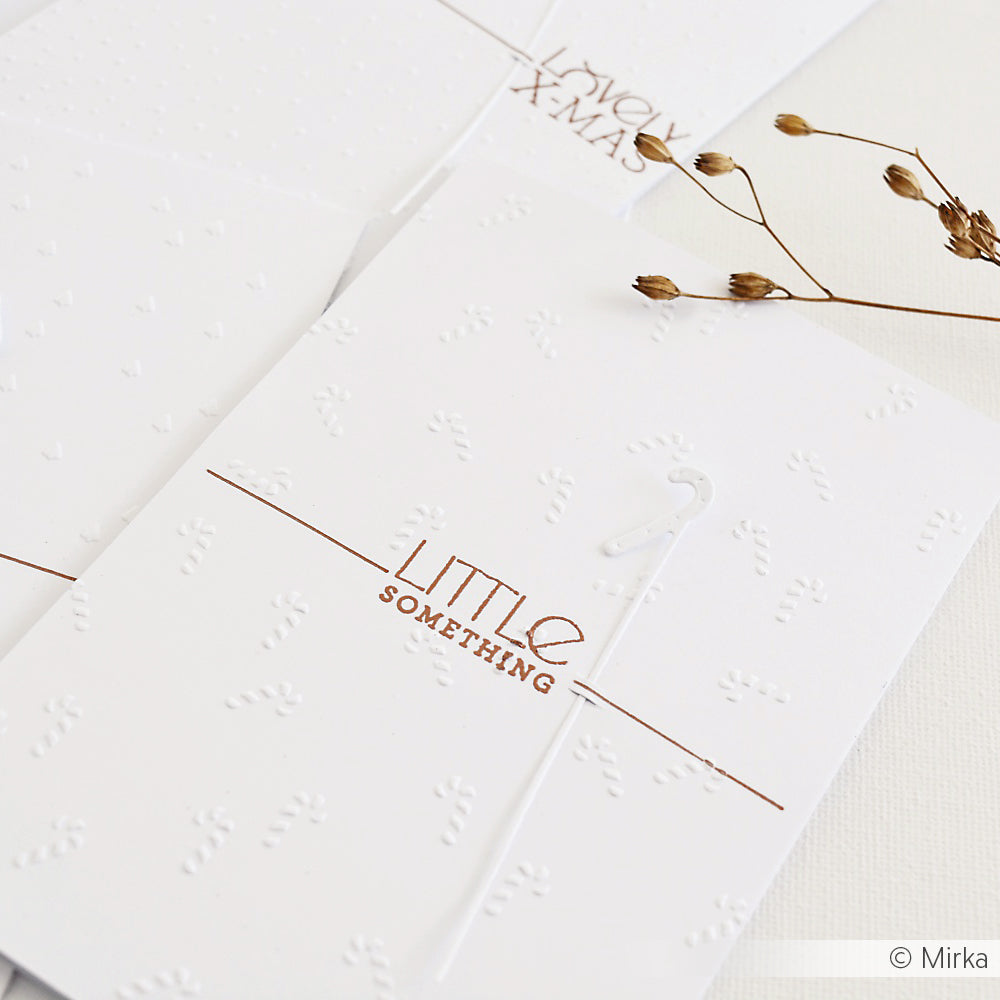 Minimalistische weiße Karte von Alexandra Renke, die mit einem Prägefolder für erhabene Muster, kupferfarbenem "Little Something"-Text und einer kleinen weißen Zuckerstange gestaltet wurde - perfekt für Designpapier-Fans.