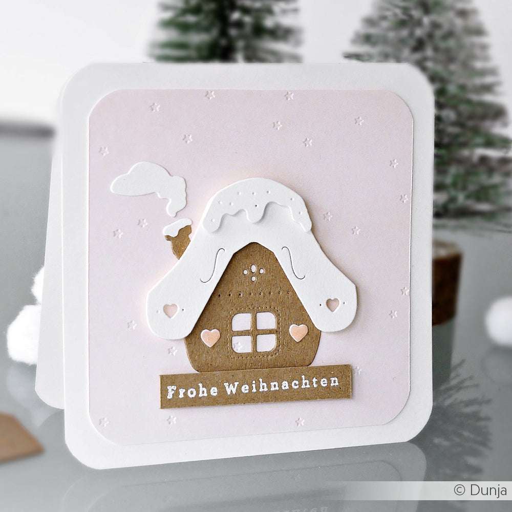 Handgemachte Weihnachtskarte von Alexandra Renke mit einem Lebkuchenhaus, dem Text Frohe Weihnachten", verschneiten Bäumen, einer mit dem Embossing Folder geprägten Textur und einem Hauch von Sternenregen-Zauber für festlichen Charme.
