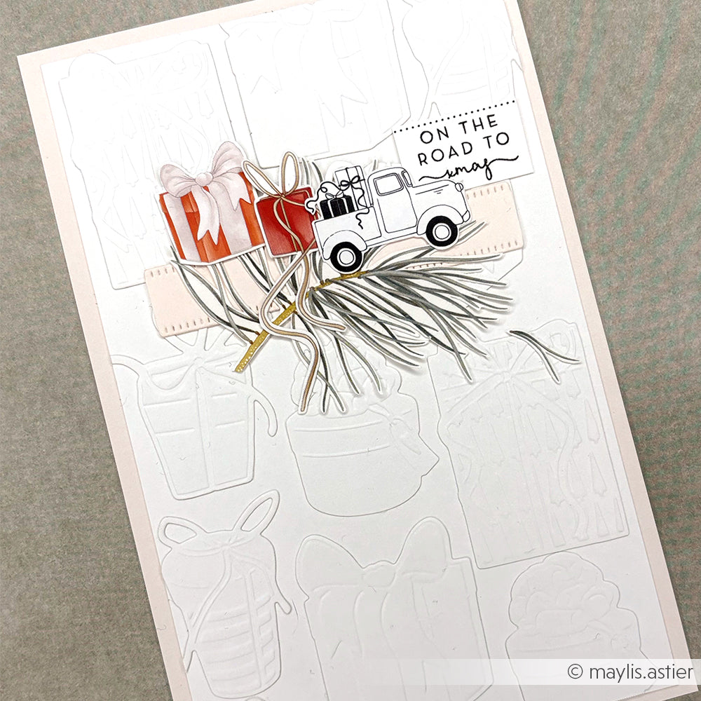 Handgefertigte Alexandra Renke Karte mit weißem Prägedesign, roten Geschenken, Tannenzweigen und einem LKW mit "On the Road to Xmas" - ideal für Liebhaber von Christbaumzauber oder Rub-On Figurenwelt und Transferfolien Basteln.