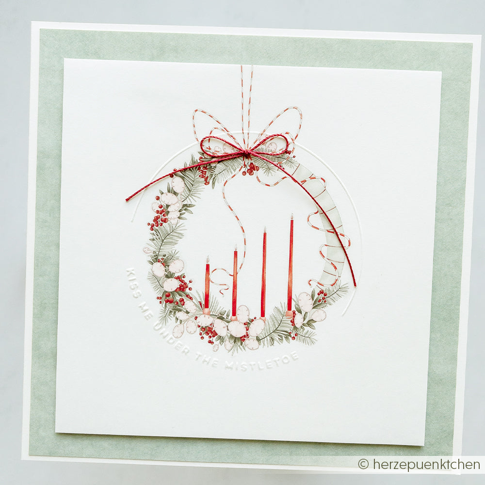 Handgefertigte Karte mit Kranz, roten Kerzen und Schleife, verziert mit festlichem Grün und Beeren - veredelt mit dem Rub-On-Motiv von Alexandra Renke aus der Adventsglanz-Kollektion für zusätzlichen Weihnachtszauber.
