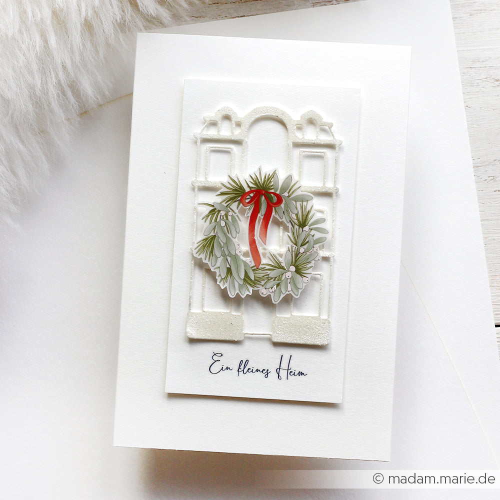 Handgefertigte Karte von Alexandra Renke mit einem festlichen Kranz und rotem Band auf einem weißen Bogen, mit dem Text "Ein kleines Hiiam" darunter. Ideal zum Motiv Aufbringen oder zum Hinzufügen von Rub-On Figurenwelt Adventsglanz zu Ihren Projekten.