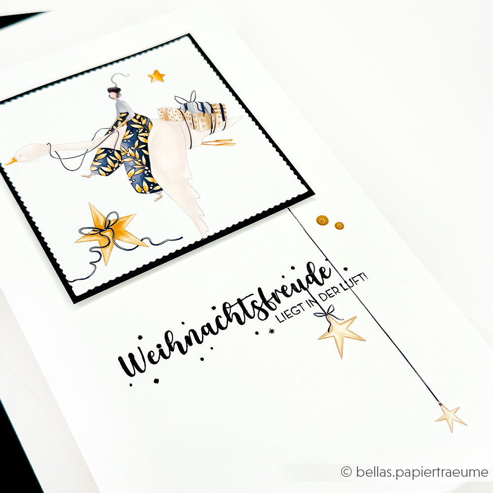 Handgemachte Weihnachtskarte von Alexandra Renke mit festlichen Illustrationen, Sternen und dem Text "Weihnachtsfreude liegt in der Luft!" Der Rub-On Figurenwelt Sternenzauber verleiht Ihren Bastelprojekten einen magischen Touch.