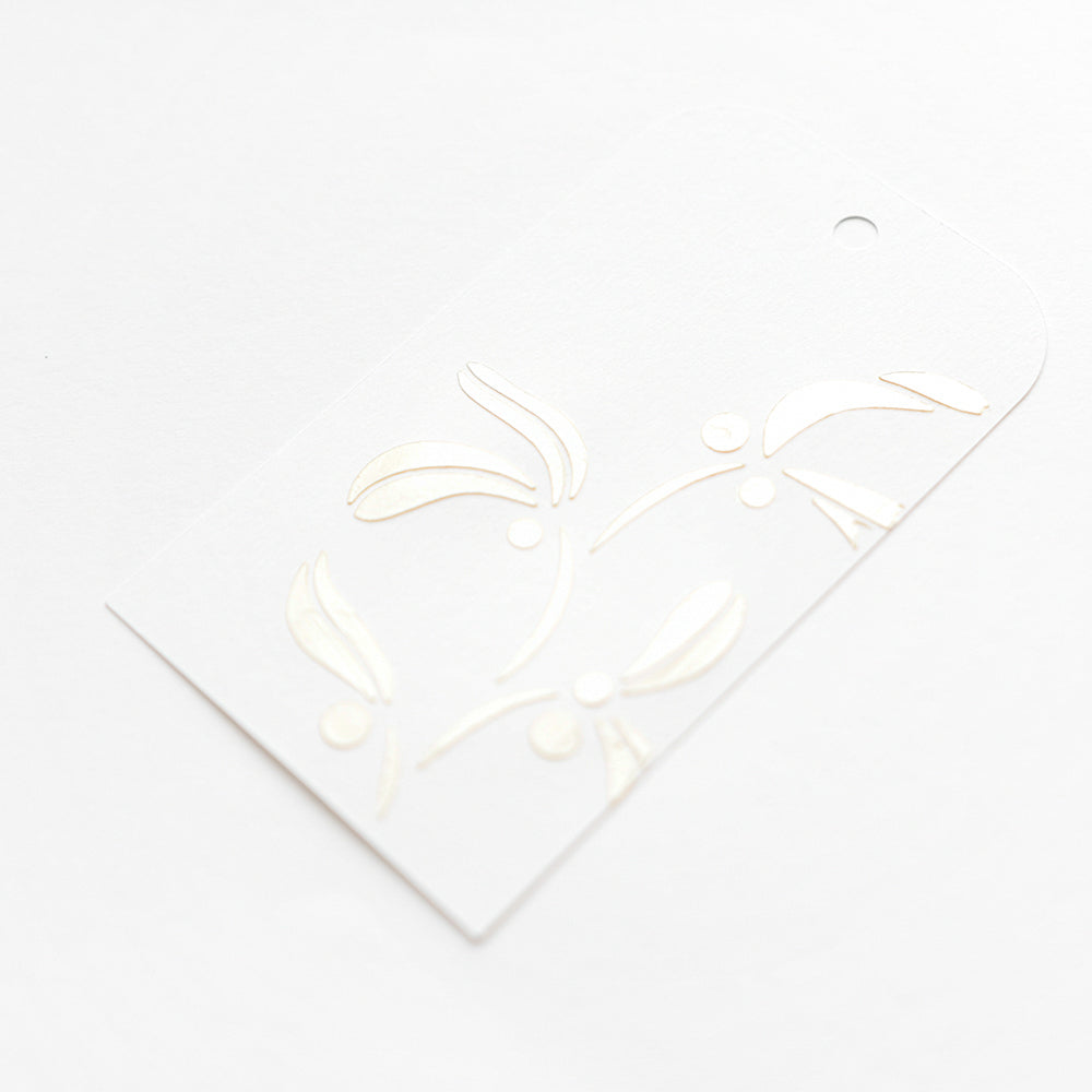 Weißer Geschenkanhänger von Alexandra Renke mit geprägtem, goldglänzendem Mistelmotiv auf weißem Hintergrund - ideal für Schablonen Papierprojekte. Mit Kordelloch und einer wiederverwendbaren Schablone Geschwungener Mistelzweig.