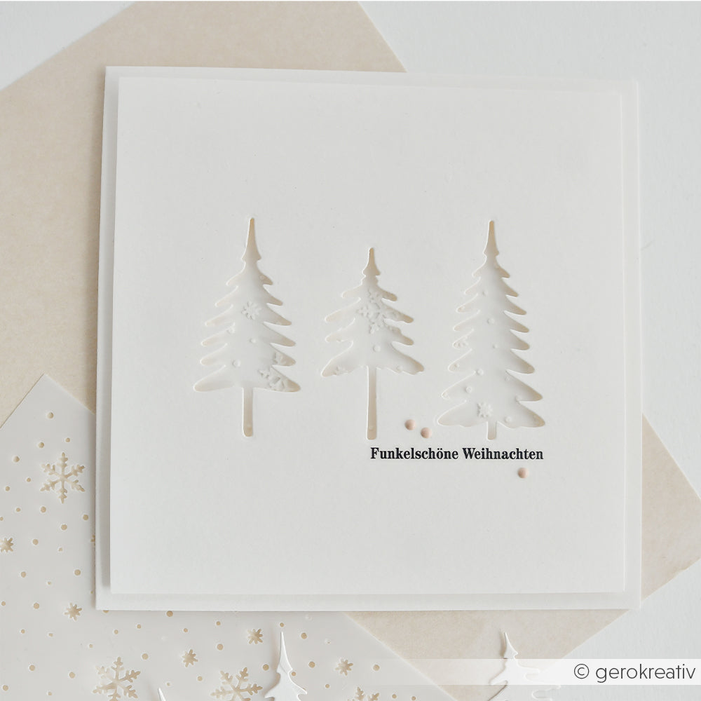 Weiße quadratische Karte mit drei ausgestanzten Tannenbäumen, dem Schriftzug Funkelschöne Weihnachten und Schablonenmotiven.
