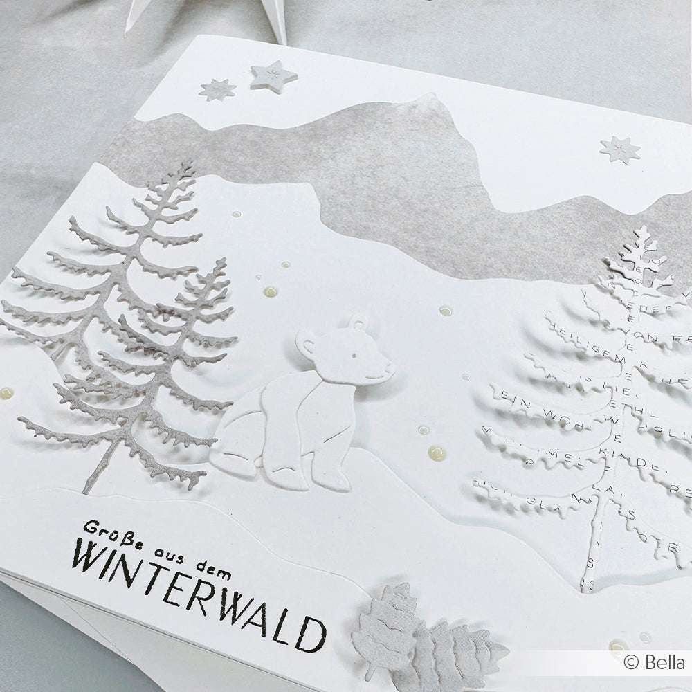 Weiße Winterkarte von Alexandra Renke mit Bäumen, einem Eisbären, Bergen und "Grüße aus dem Winterwald" auf Deutsch, erstellt mit Photopolymer-Klarsichtstempeln für gestochen scharfe Details, inspiriert von Winterwalds Magie.