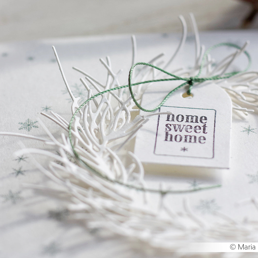 Ein weißer Anhänger mit "home sweet home" auf einem dekorativen Kranz, gebunden mit grüner Schnur - perfekt zum Basteln mit Ihren Lieblingsstempeln Alexandra Renke Clear Stamps oder Photopolymer Stempel für eine persönliche Note.