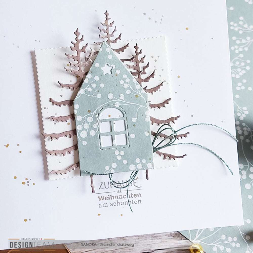 Handgefertigte Weihnachtskarte von Alexandra Renke mit einem blauen Haus, Bäumen, Schneeakzenten und dem Text "Weihnachten am schönsten". Hergestellt mit hochwertigen Clear Stamps für gestochen scharfe, festliche Details.