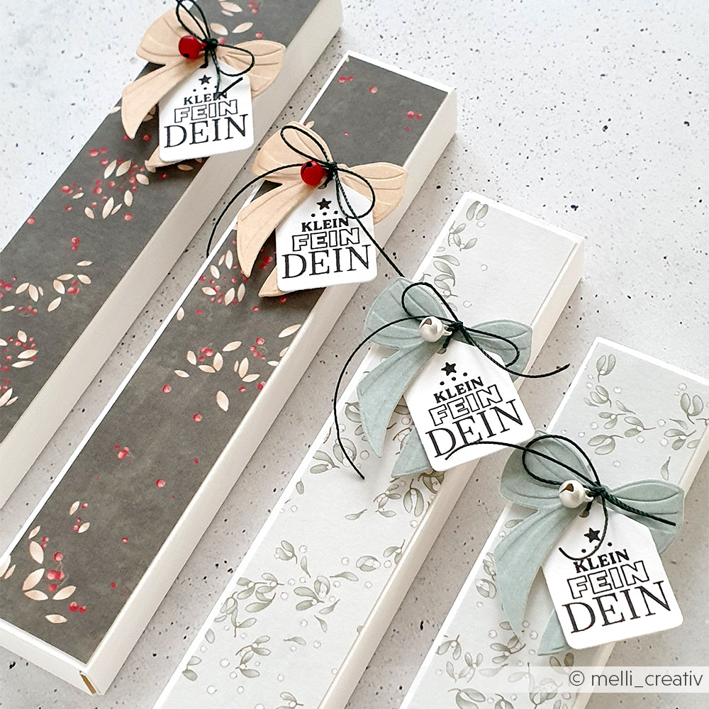 Vier schlanke Alexandra Renke Geschenkboxen mit floralen Mustern, die jeweils mit Anhängern, Schleifen und kleinen Ornamenten verziert sind - perfekt, um handgefertigte Geschenke zu präsentieren, die mit Clear Stamp Bastelzubehör hergestellt wurden.