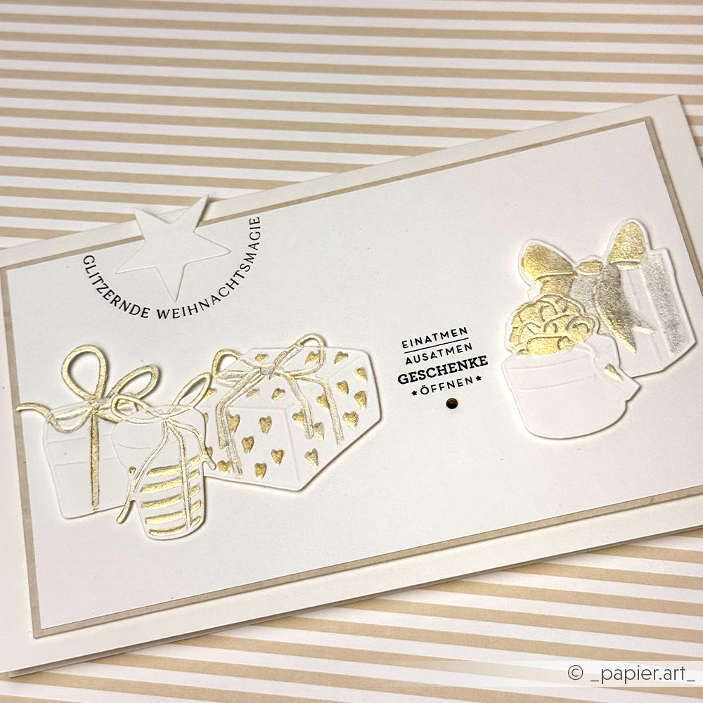 Alexandra Renke Weihnachtskarte in Weiß und Gold mit Geschenkillustrationen und deutschen Weihnachtsgrüßen auf gestreiftem Hintergrund - ideal für die Weihnachtszeit.