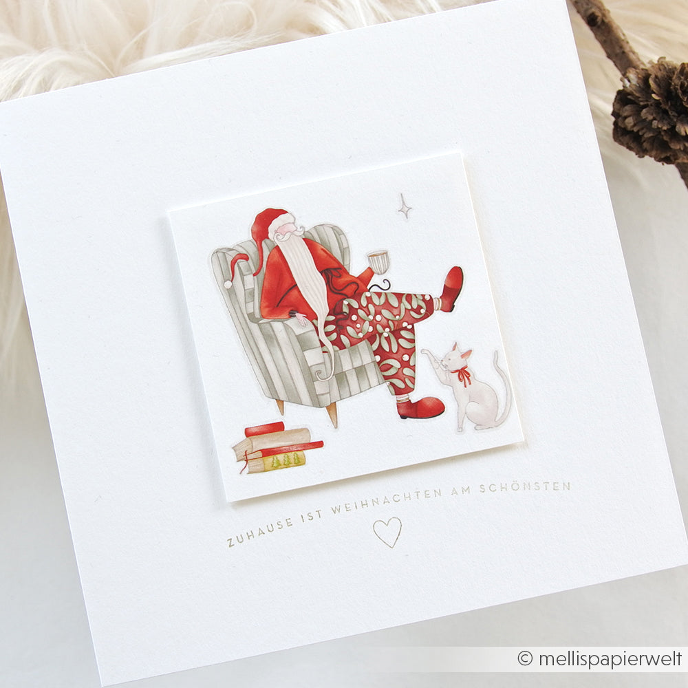 Illustration des Weihnachtsmanns, der sich mit einer Katze, Büchern und einer Tasse auf einer weißen Weihnachtskarte von Alexandra Renke ausruht - ideal, um den Adventszauber mit Ihrem bevorzugten Clear Stamp oder Photopolymer-Stempel festzuhalten.