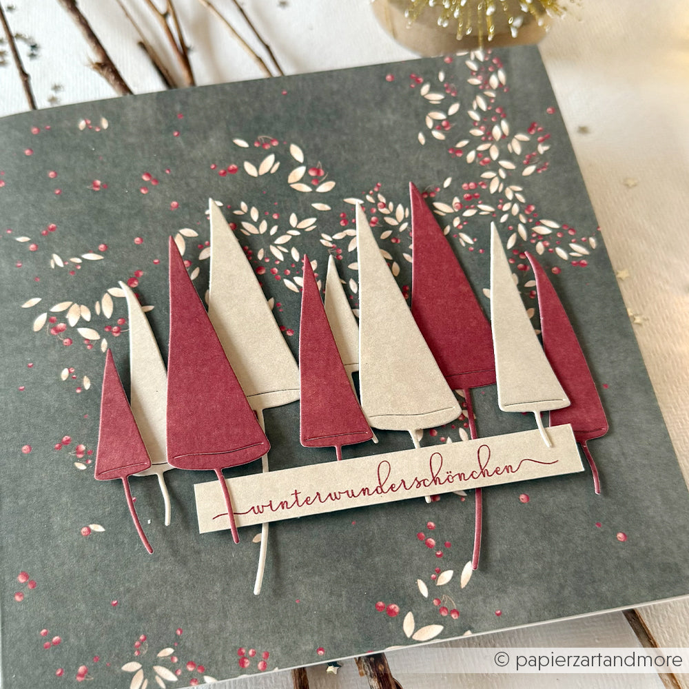 Handgemachte Karte von Alexandra Renke mit roten und cremefarbenen Papierbäumen, "Winterwunderschönchen" in roter Schrift und zarten Eiskristallträumen, die mit einem Klarsichtstempel gestempelt wurden.