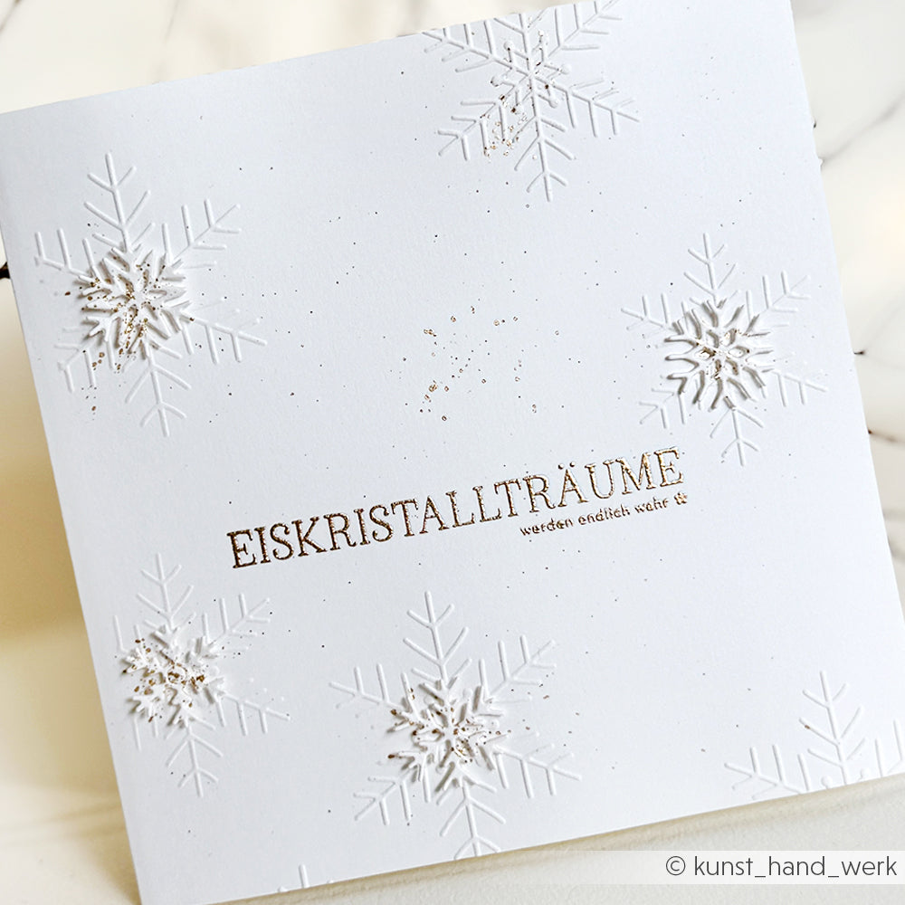 Weiße Weihnachtskarte von Alexandra Renke mit geprägten Schneeflocken und dem deutschen Text "Eiskristallträume" in der Mitte - ideal für die Kombination mit Ihren Lieblingsmotiven aus Photopolymer-Klarsichtstempeln.